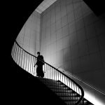person walking on stairs in greyscale photograph